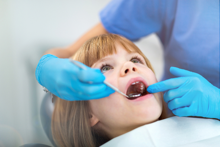 bambina sulla poltrona del dentista si sottopone a visita di odontoiatria pediatrica
