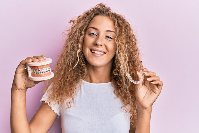 Beautiful caucasian teenager girl holding invisible aligner orthodontic and braces smiling with a happy and cool smile on face. showing teeth.