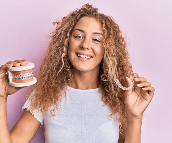Beautiful caucasian teenager girl holding invisible aligner orthodontic and braces smiling with a happy and cool smile on face. showing teeth.
